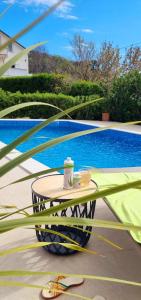 a table with two cups on it next to a pool at Apartments Čule in Rab