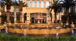 a fountain in front of a building with palm trees at Urban Island Hotel Shanghai in Jiading