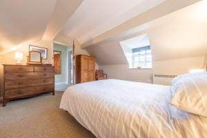 a bedroom with a white bed and a dresser at Garden Cottage in Ringstead