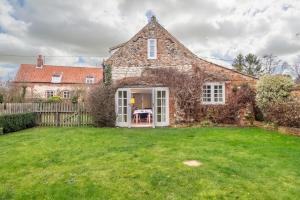 an old stone house with a grass yard at Garden Cottage in Ringstead