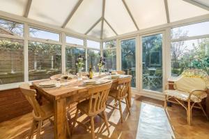 a conservatory with a wooden table and chairs and windows at Plunketts Cottage in Brancaster
