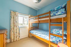 two bunk beds in a blue room with a window at Plunketts Cottage in Brancaster