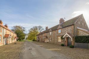 a row of brick houses on a dirt road at Plunketts Cottage in Brancaster