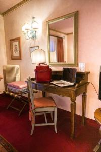 a room with a desk with a laptop and a mirror at Hotel Boccaccio in Calcinaia