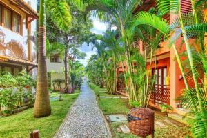 un jardín con palmeras junto a un edificio en Pipa Beleza Ap aconchegante en Pipa