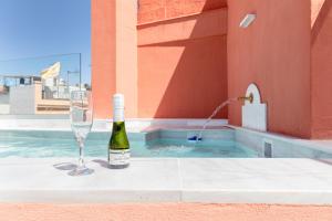een fles wijn en een wijnglas naast een zwembad bij Casa Palacio Virgenes 7 with private swimming pool and parking in Sevilla