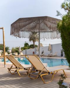 a pair of chairs and an umbrella next to a pool at Casa Blue Sarantis in Faliraki