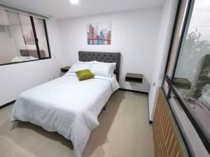 een slaapkamer met een wit bed met een groen kussen bij Encantador apartamento #2 cerca al aeropuerto in Bogota