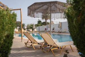 2 ligstoelen en een parasol naast een zwembad bij Casa Blue Sarantis in Faliraki