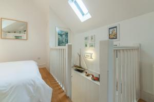 a white bedroom with a bed and a mirror at Newgate Boathouse in Wells next the Sea