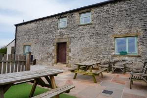 a patio with picnic tables and a stone building at The Holmes Barn - Sleeps 16 - Peak district in Buxton