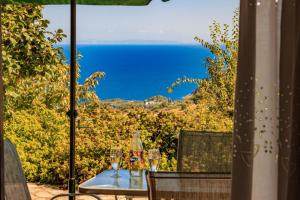 a table with wine glasses sitting on a patio with the ocean at Villa Zina Agios Dimitrios in Agios Dimitrios