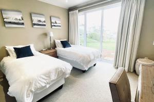 um quarto com 2 camas e uma grande janela em Exquisite Villa at Pinnacle em Mossel Bay