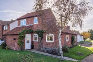 a brick house with a tree in the front yard at Sea Lodge in Brancaster
