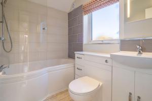 a white bathroom with a toilet and a sink at Sea Lodge in Brancaster +20 photos