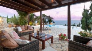un patio con sofás, una mesa y una piscina en Avlaki Bay House, en Arvanitakaíïka