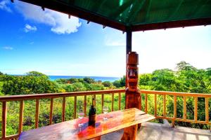 un banco de madera en un balcón con una botella de vino en Hotel Tekarera - Kainga Nui, en Hanga Roa