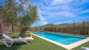 a swimming pool with two chairs and a tree in a yard at Casa Los Bartolos Vélez Rubio by Ruralidays in Vélez Rubio