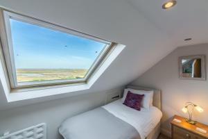 a bedroom with a window with a bed in it at 4 Harbour View in Brancaster