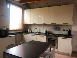 cocina con armarios blancos, mesa y fregadero en Bondion Apartment, en Sandra