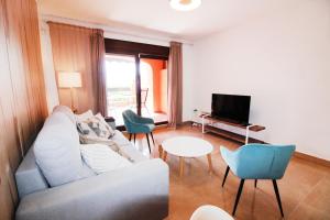 ein Wohnzimmer mit einem Sofa, Stühlen und einem TV in der Unterkunft APARTAMENTO DEL MAR - Playa Del Angel-Estepona in Estepona