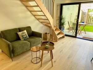 sala de estar con sofá verde y escalera en La petite Maison Messigny, en Vantoux