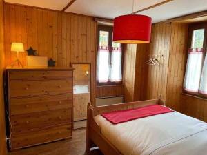 a bedroom with a bed and a dresser and a red lamp at Charmant 2,5 pièces avec jardin à 2 pas du lac in Champex