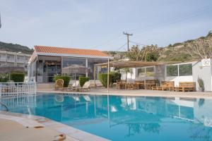 a swimming pool with tables and chairs next to a building at Casa Blue Sarantis in Faliraki
