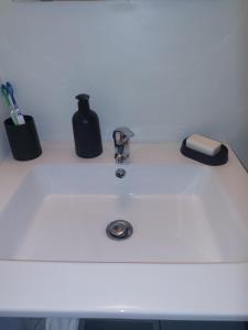 un lavabo con un dispensador de jabón negro. en Studio 10 min aéroport orly, en Athis-Mons