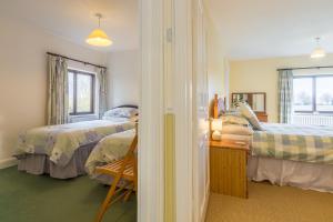 a bedroom with two beds and a desk and a window at Keepers Cottage in Fakenham