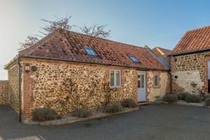 a brick house with a stone wall at Geddings Farm Barn in Ringstead