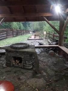 a stone fireplace in a yard with a wooden fence at Domek w Dolinie Zimnika in Lipowa