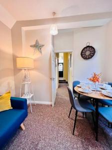 a living room with a table and blue chairs at Beach Vibes in Southend-On-Sea by Artisan Stays I Free Parking I Bank Holiday Offer in Southend-on-Sea