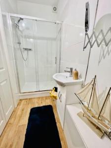 a white bathroom with a sink and a shower at Beach Vibes in Southend-On-Sea by Artisan Stays I Long Weekend Offer I Free Parking in Southend-on-Sea