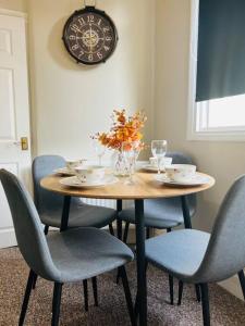 a dining room table with chairs and a clock on the wall at Beach Vibes in Southend-On-Sea by Artisan Stays I Leisure or Business I Free Parking I Sleeps 5 in Southend-on-Sea