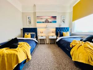 um quarto com duas camas com amarelo e azul em Beach Vibes in Southend-On-Sea by Artisan Stays I Free Parking I Contractors & Families I Sleeps 5 em Southend-on-Sea