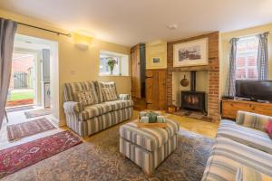 a living room with two chairs and a fireplace at 1 Honeymoon Row in Wells next the Sea