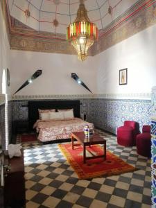 una camera con letto, tavolo e lampadario a braccio di Riad Freija-TAROUDANT a Sidi Abd el Kader