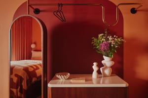a bedroom with a table with a vase and a mirror at Ember Locke Kensington in London