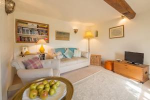 sala de estar con sofá y TV en Brooke Cottage en Little Walsingham