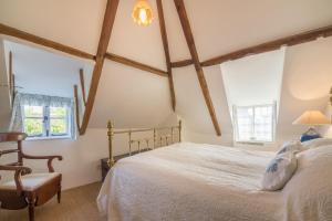 a bedroom with a white bed and two windows at Brooke Cottage in Little Walsingham