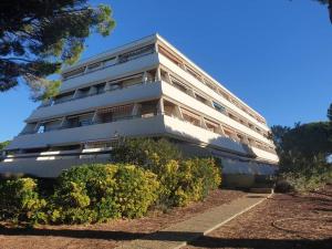 un bâtiment blanc avec des buissons devant lui dans l'établissement En bord de mer, avec Grande terrasse et Climatisation, au Grau-du-Roi