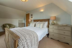 a bedroom with a large white bed and a dresser at Forge Cottage in Thornham