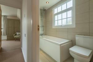 a bathroom with a toilet and a tub and a window at Forge Cottage in Thornham +24 photos