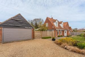 a detached house with a garage in a driveway at Forge Cottage in Thornham