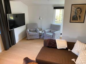 ein Wohnzimmer mit einem Sofa, 2 Stühlen und einem Flachbild-TV in der Unterkunft Casa Blanca in Strandbaden
