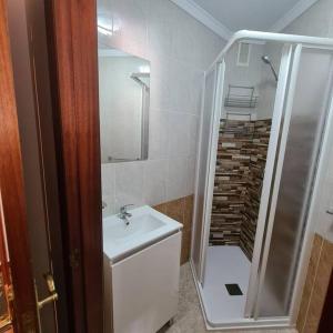 uma casa de banho branca com um lavatório e um chuveiro em piso en noia em Noya