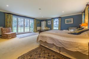 a bedroom with a large bed with blue walls andwindows at Grooms Cottage C in Grimston