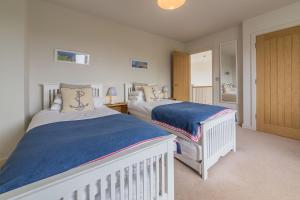 a bedroom with two beds and a door to a bathroom at Anchorage in Brancaster