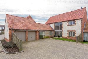 a brick house with a garage and a driveway at Anchorage in Brancaster
